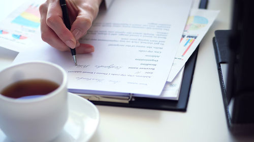 Midsection of woman writing in book