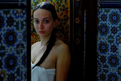 Portrait of woman by patterned wall in bathroom