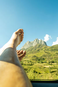 Close-up of a girl's feet in a window with a mountain in the background