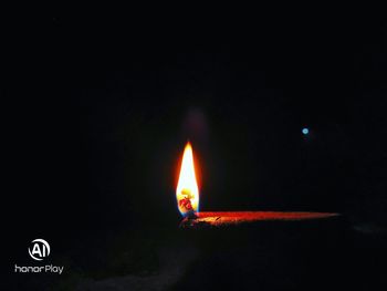 Close-up of lit candle against black background