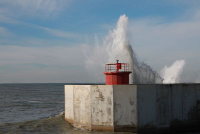 Lighthouse by sea against sky