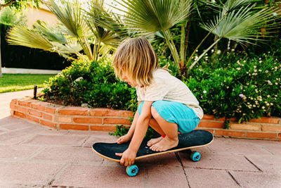 Boy on skateboard against plants