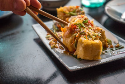 Cropped image of hand holding tofu with chopsticks