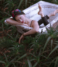 Full length portrait of woman lying in abandoned bathtub on grass