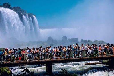 People on bridge against waterfall