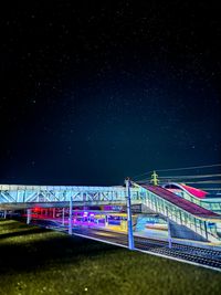 Illuminated bridge over river against sky at night