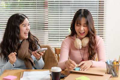 Young woman using phone while sitting on table