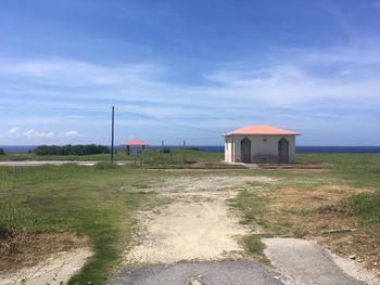 Built structure on field by road against sky