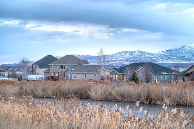 Houses on field by buildings against sky