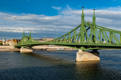 Bridge over river against cloudy sky