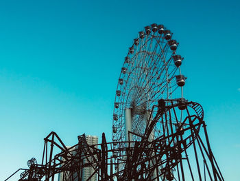 Low angle view of ferris wheel against blue sky