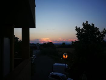 Silhouette trees and buildings against sky at sunset