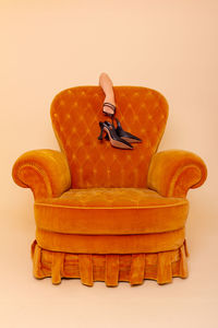 Tired woman holding shoes behind the sofa. while standing behind the yellow sofa. photo in studio. 