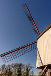 Low angle view of traditional windmill against clear blue sky