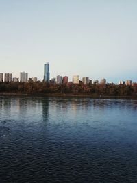 Buildings by river against clear sky