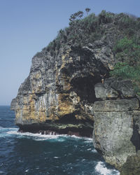 Rock formation in sea against clear sky