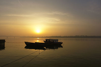 Silhouette boat in sea against sky during sunset