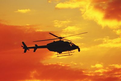 Low angle view of silhouette cranes against sky during sunset