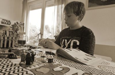 Rear view of boy sitting on table at home