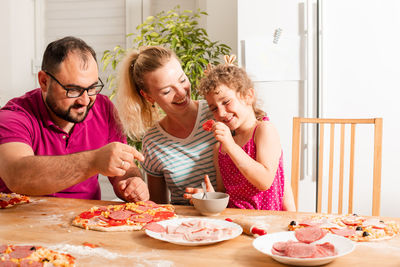 Cheerful family eating pizza at home