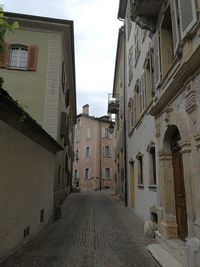 Empty road amidst buildings against sky