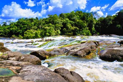 Scenic view of river stream amidst rocks against sky