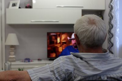 Rear view of man sitting at home