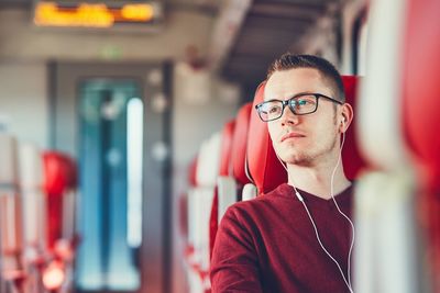 Young man listening to music while traveling in train