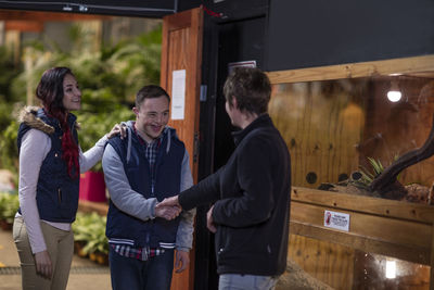 Young man with down syndrome shaking hands with woman at reptile exhibition