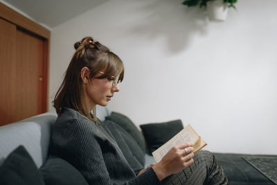 Young woman looking away while sitting on book