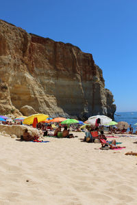 People at beach against clear sky