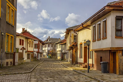 Street amidst houses in town against sky