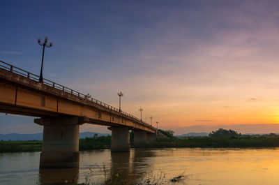 Bridge over river against sky during sunset