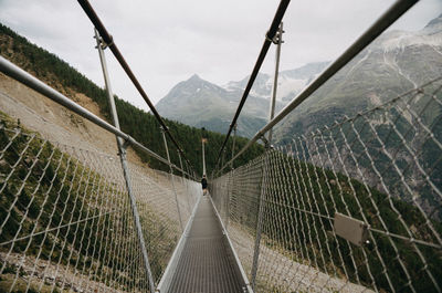 Rear view of man walking on footbridge