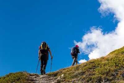 People standing on mountain against blue sky