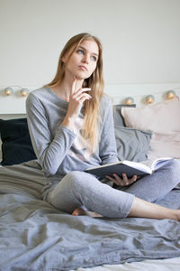 Young woman using smart phone while sitting on laptop