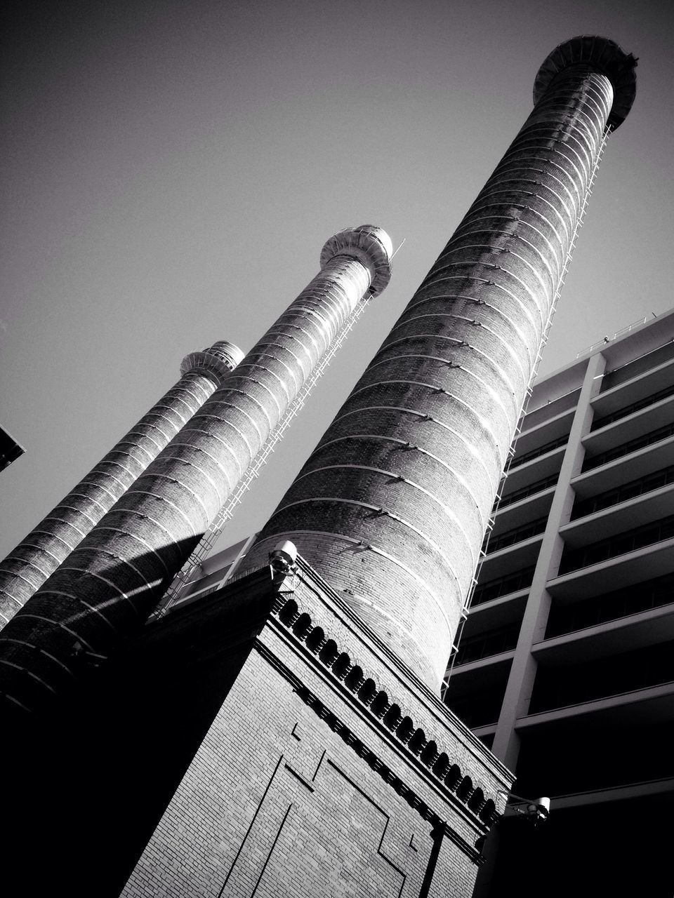 low angle view, architecture, built structure, building exterior, tall - high, tower, sky, industry, famous place, city, factory, travel destinations, capital cities, international landmark, modern, skyscraper, tilt, travel, smoke stack, no people