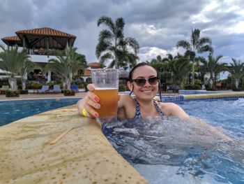 Portrait of smiling woman in swimming pool against sky