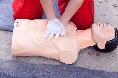 Midsection of paramedic performing cpr on mannequin