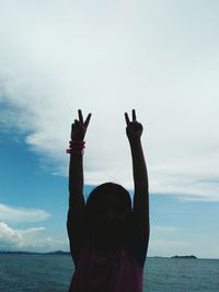 Man with arms raised in sea against sky