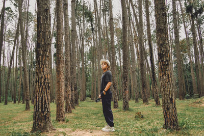 Side view of man standing by trees in forest