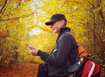 Man using phone while standing in forest during autumn