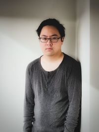 Portrait of young man standing against wall