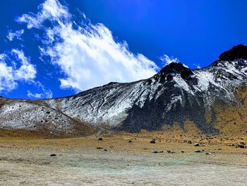 Scenic view of snowcapped mountains against blue sky