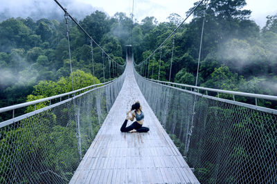 Young woman doing yoga on footbridge