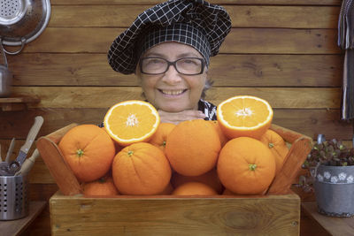 Portrait of smiling woman with orange fruits
