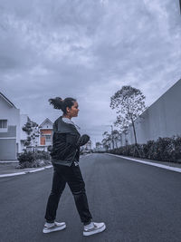 Full length of young man standing on road against sky