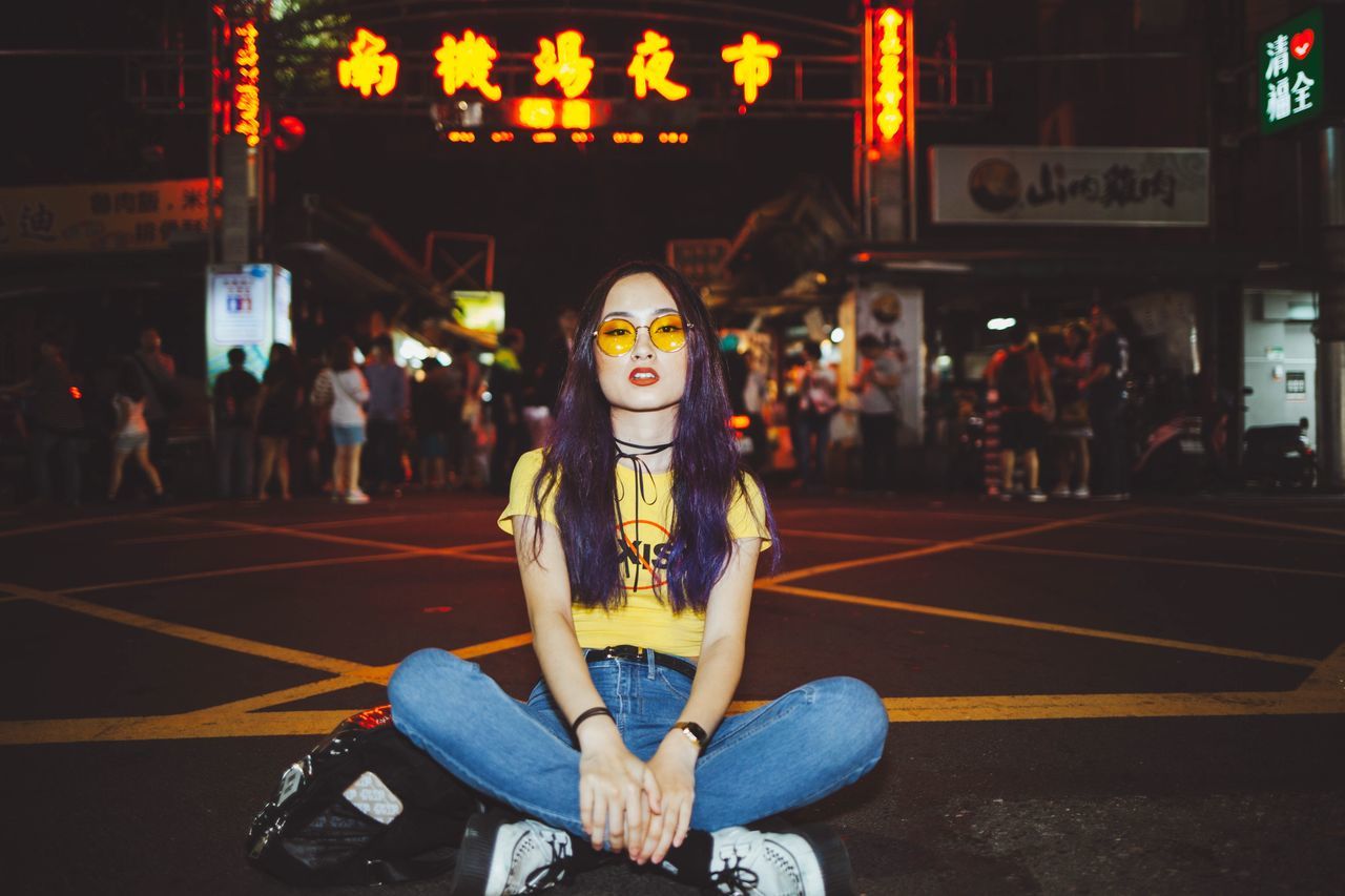 one person, sitting, real people, portrait, lifestyles, looking at camera, night, leisure activity, women, young adult, incidental people, city, illuminated, transportation, focus on foreground, front view, young women, casual clothing, architecture, hairstyle, beautiful woman