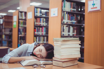 Young woman sleeping at table in library