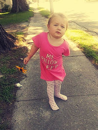 Portrait of cute girl standing on footpath